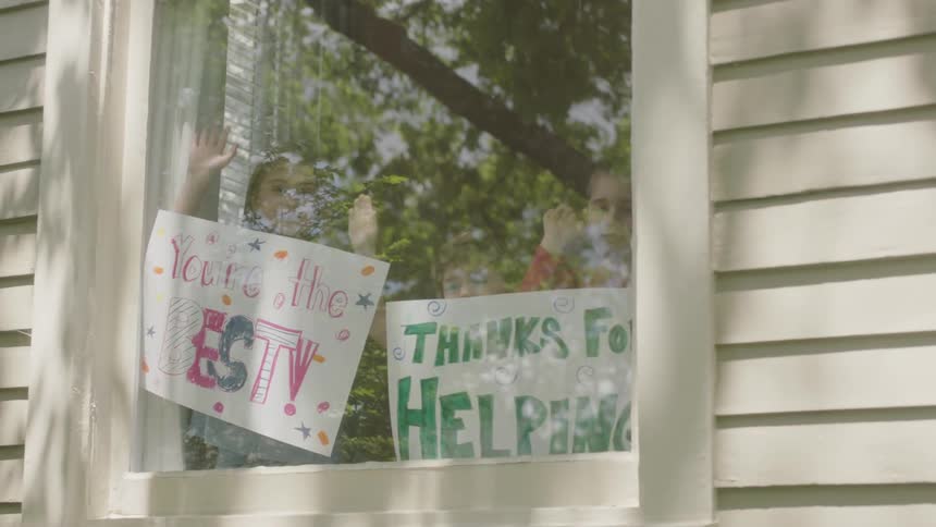Kids show welcome signs on window while waving
