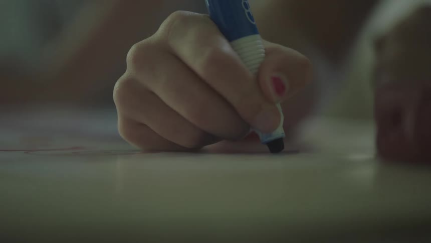 A teenage girl uses a blue marker to make a poster