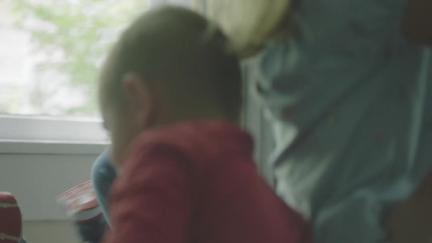 A woman laughs and lies on the floor with her children