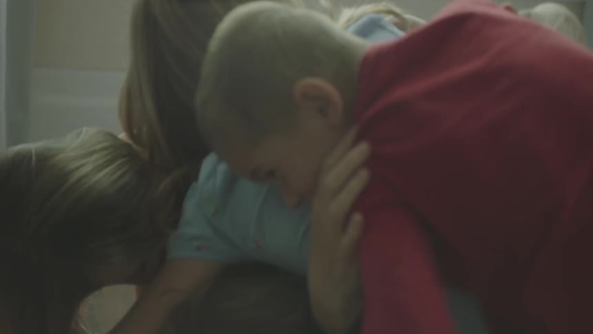 A young girl playfully attacks her mother to the floor and other children join in