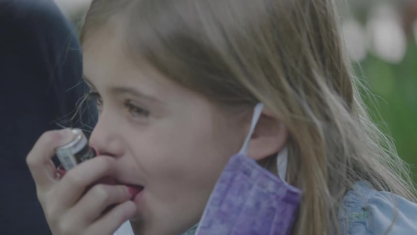 A child is comforted while using an asthma inhaler
