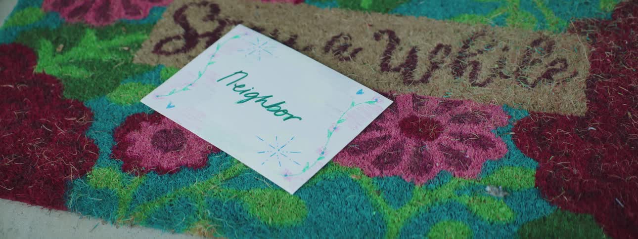 A card addressed to neighbor is dropped on a welcome mat