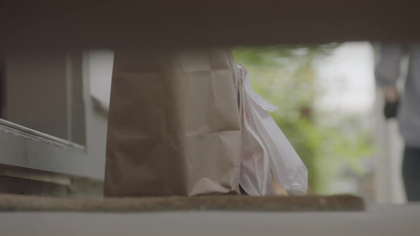 A person delivers a bag with items and prescriptions to the porch of another person