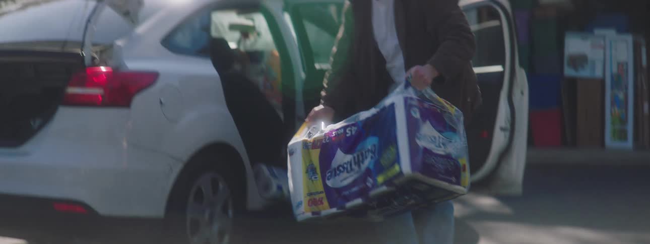 Man unloads groceries from parked car