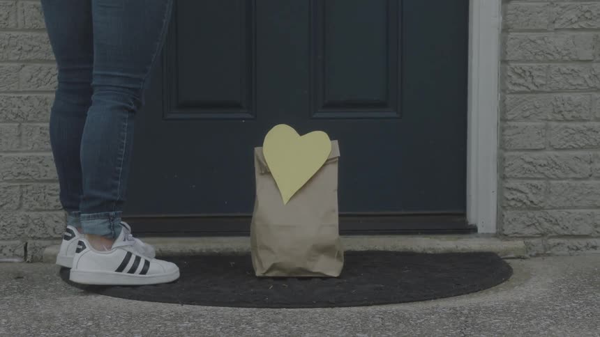 Delivery person leaves bag with a heart sign on it at the door