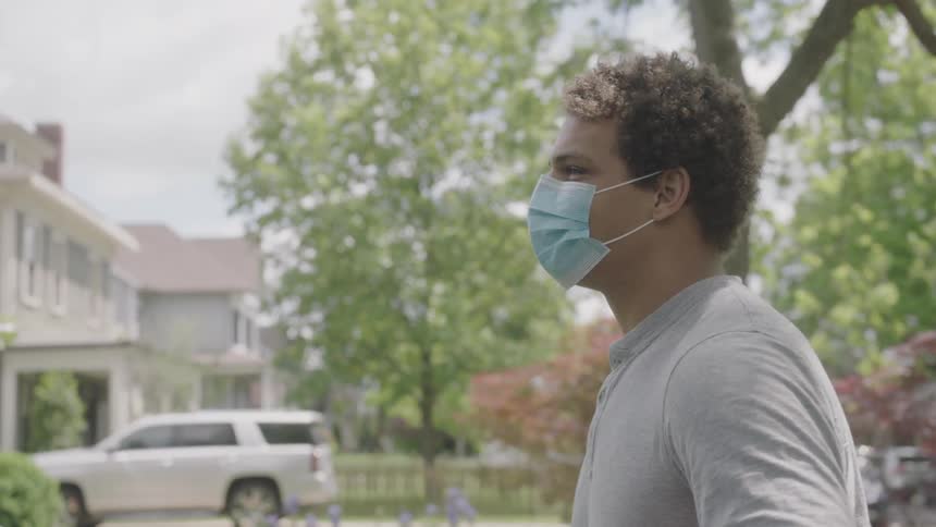 Man wearing a face mask as a precaution against the coronavirus walks in the front garden