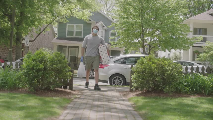 A man takes toilet paper out of his car and carries it