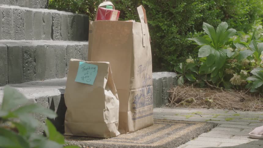 Person delivering food purchase on front step of a home