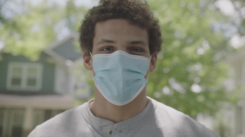 Young man wearing face mask looks at the camera