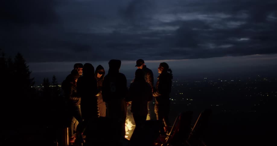 Friends hanging out around a bonfire by the lake at night