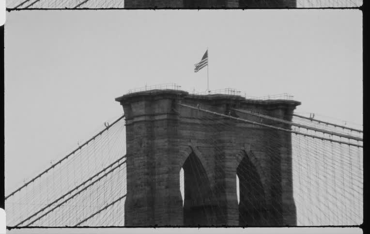 American flag blowing in the wind atop a column from a bridge