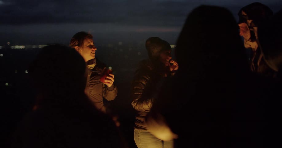 Friends gather around a bonfire at night