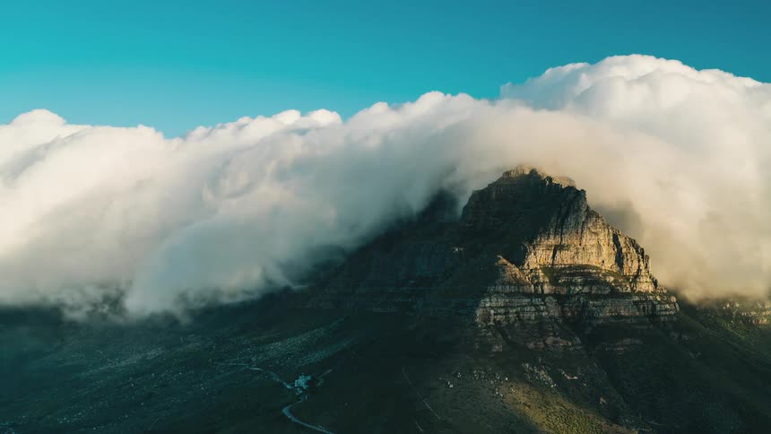 Time lapse of clouds rolling over mountain top at day