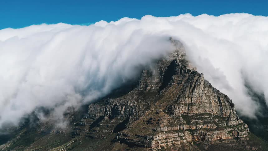 Time lapse of clouds flowing over mountaintop at day