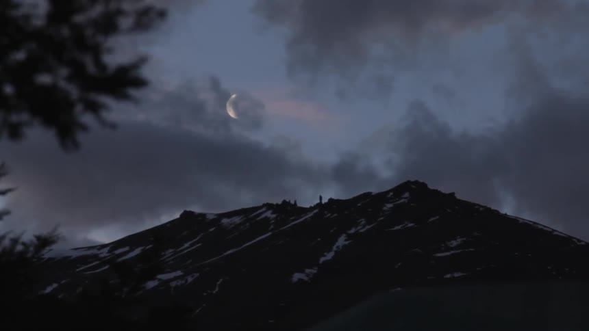 Clouds cover the moon over a mountain