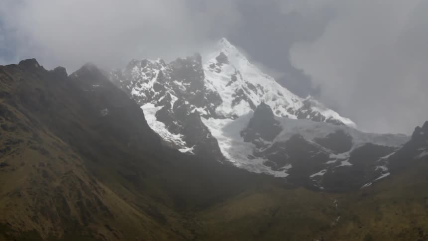 Clouds float over a snowy mountain