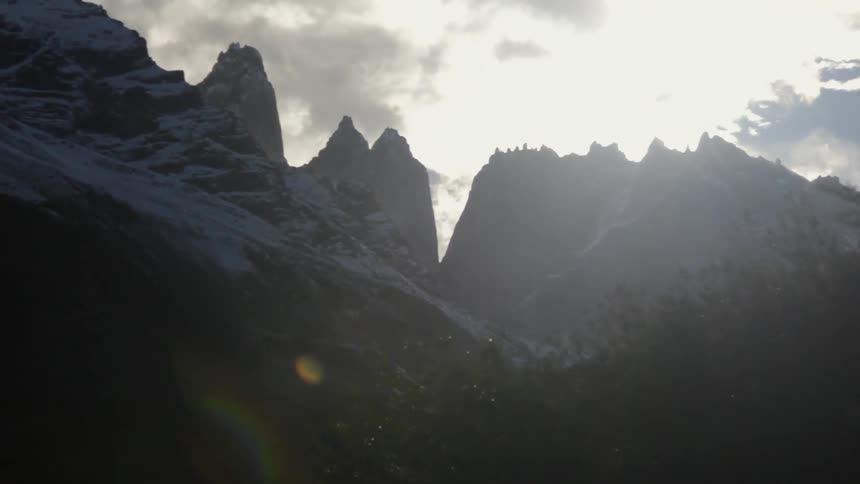 The sun shines through clouds over the mountains