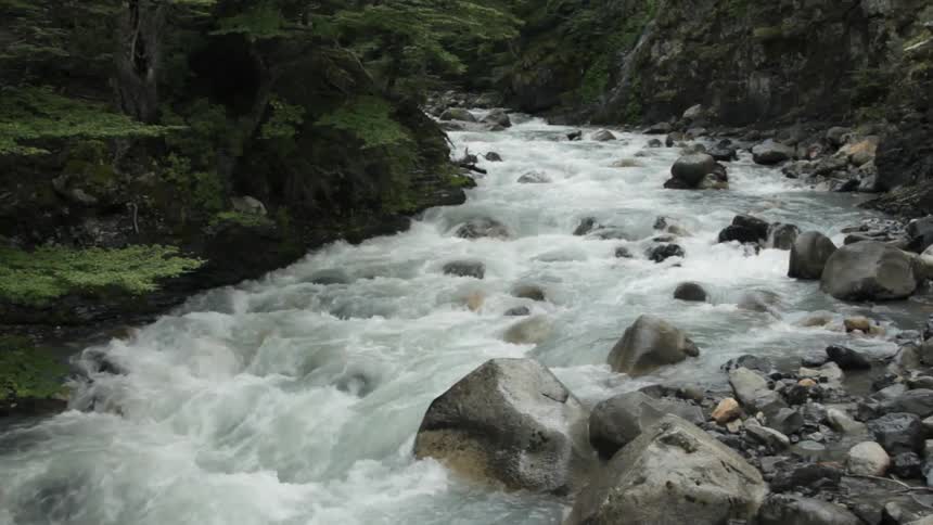 Water is traveling fast over some rocks in a rapid