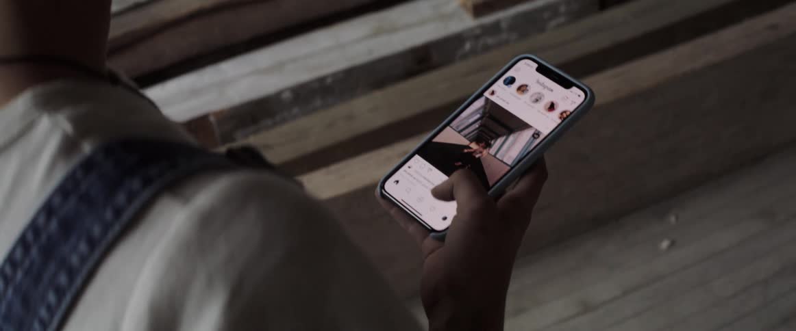 A woman is holding and looking at a smart phone