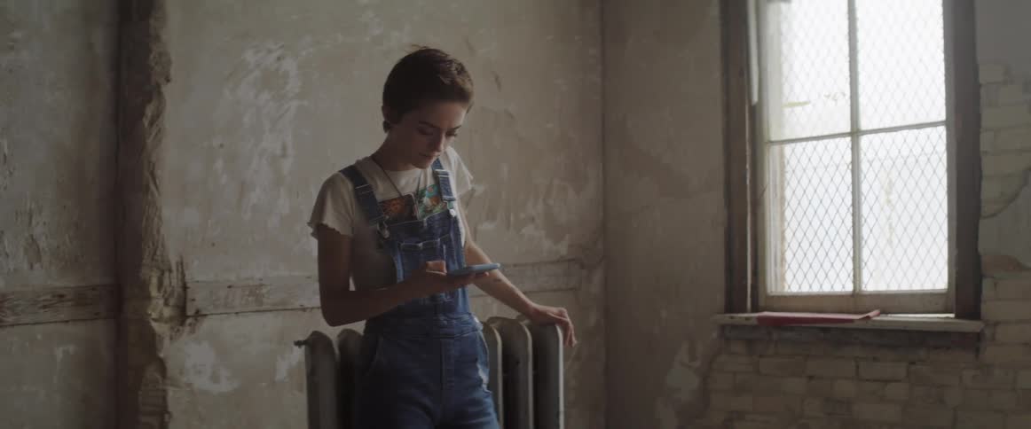 A woman is holding a cellphone in a room