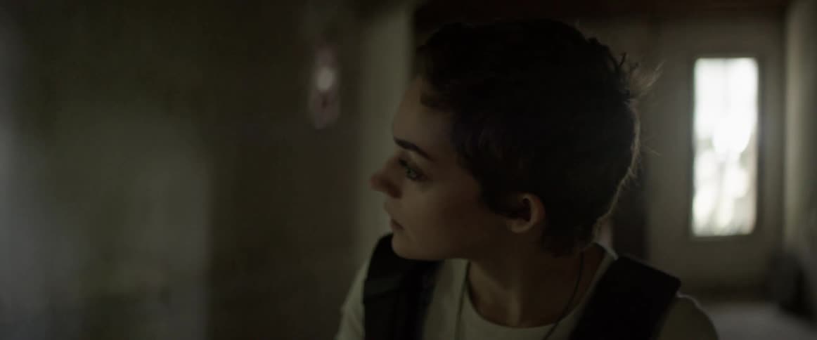 A woman shines a flashlight in a dark hallway while looking around