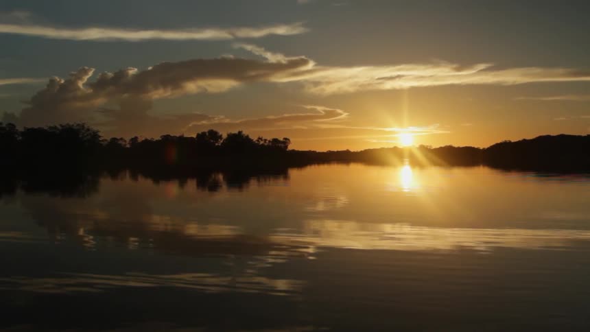 The sun is setting in the distance past the water