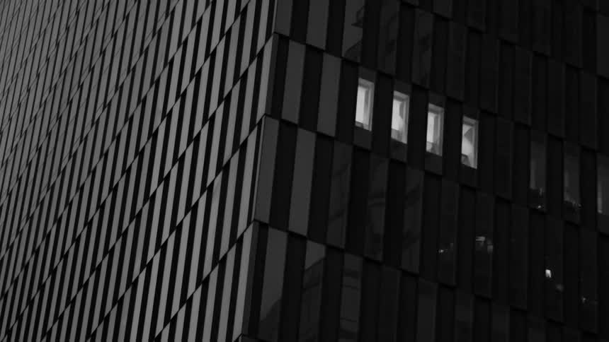 Lights and surrounding buildings reflect on a skyscrapers facade