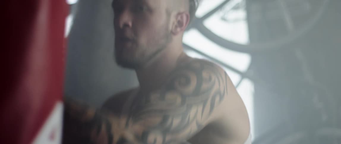 A tattooed box training by aggressively attacking a punching bag