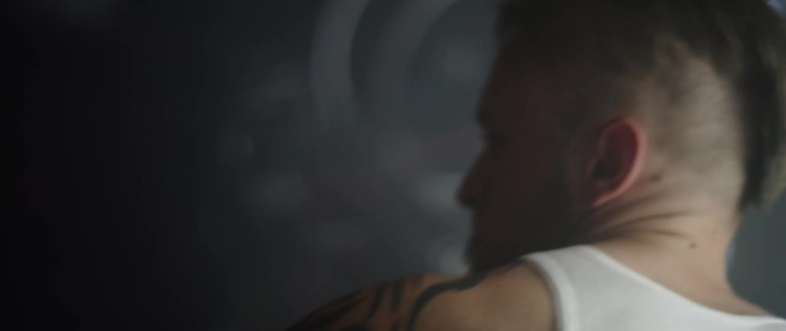 A man with taped up hands punching a heavy bag