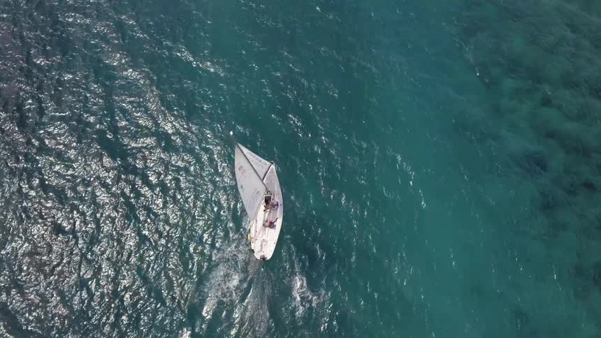A white sailboat sail on a calm ocean on a sunny day