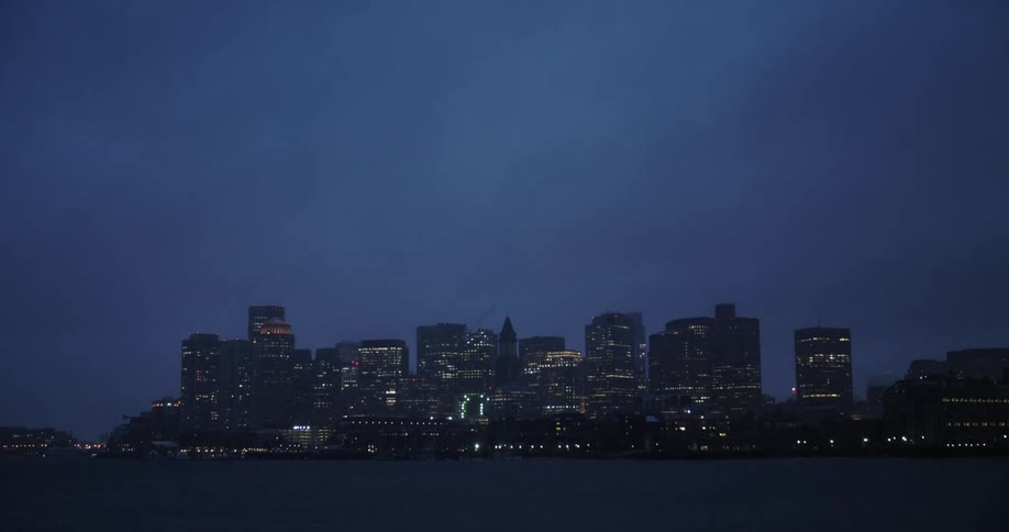Clouds float about a city skyline at night