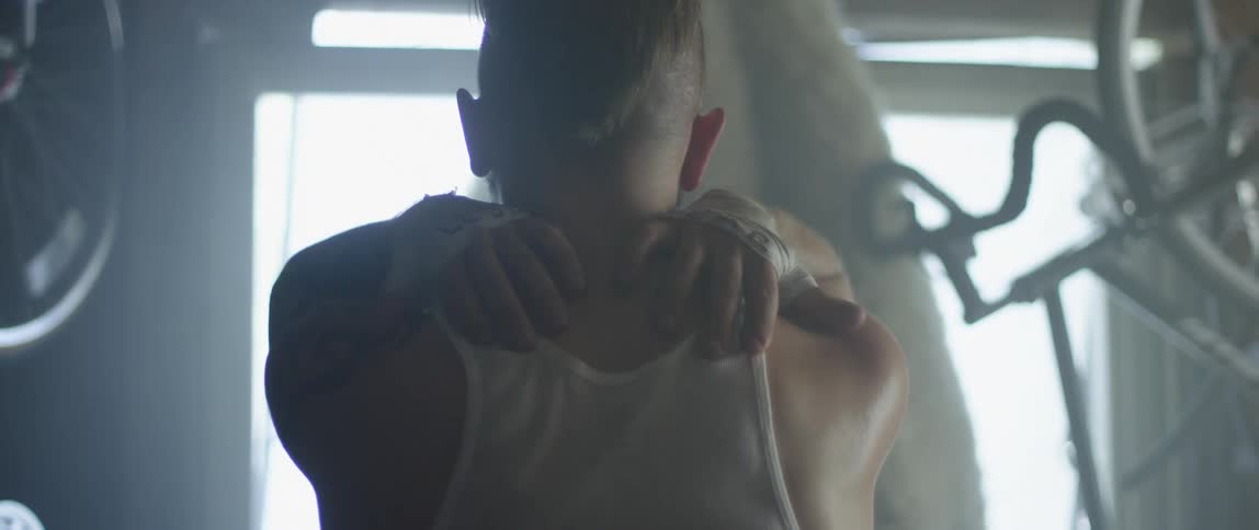 A man in a wife beater rubs his shoulders