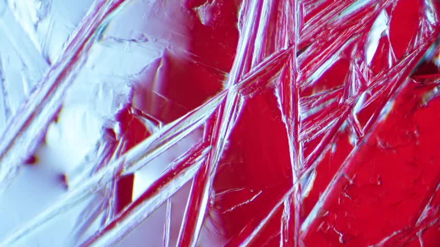 Abstract crystals grow under a microscope using polarising filter