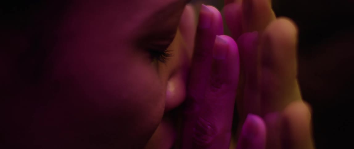 A woman holds her hand up against glass where another hand is