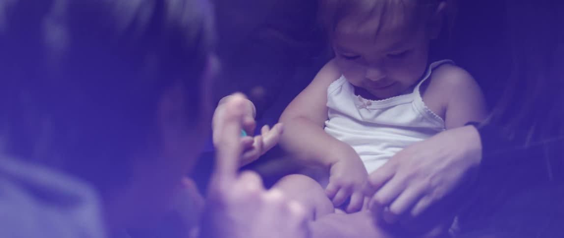 A dad watches and claps as mom helps baby girl roll play doh