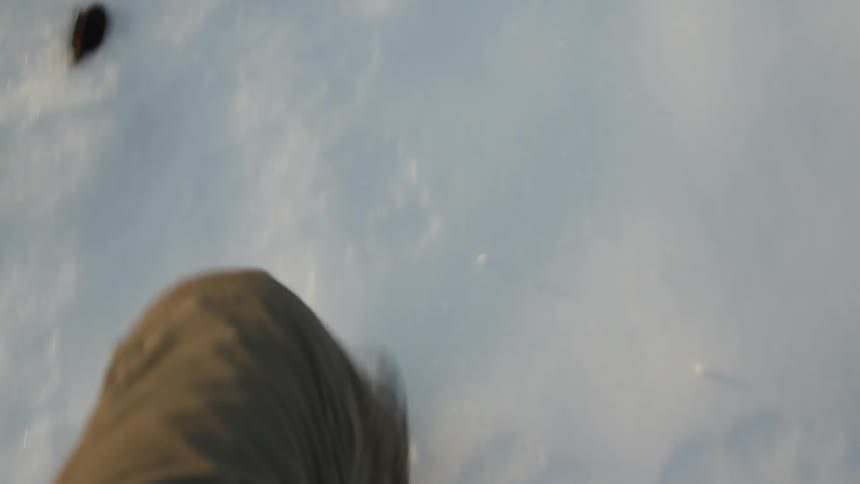 A person is walking through some snow towards rocks