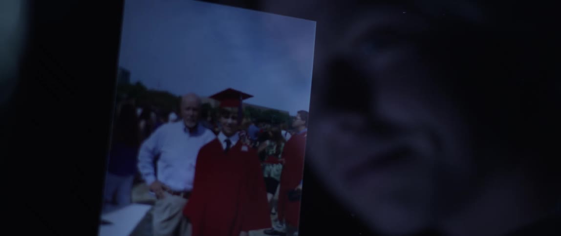 A teenager looks at a photo from his graduation
