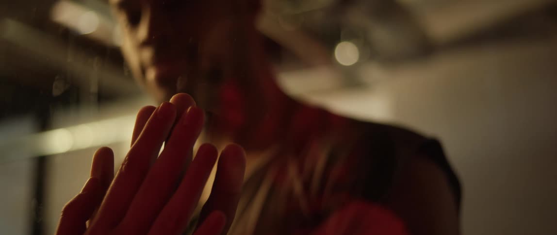 A man touches a womans hand by holding it up to glass