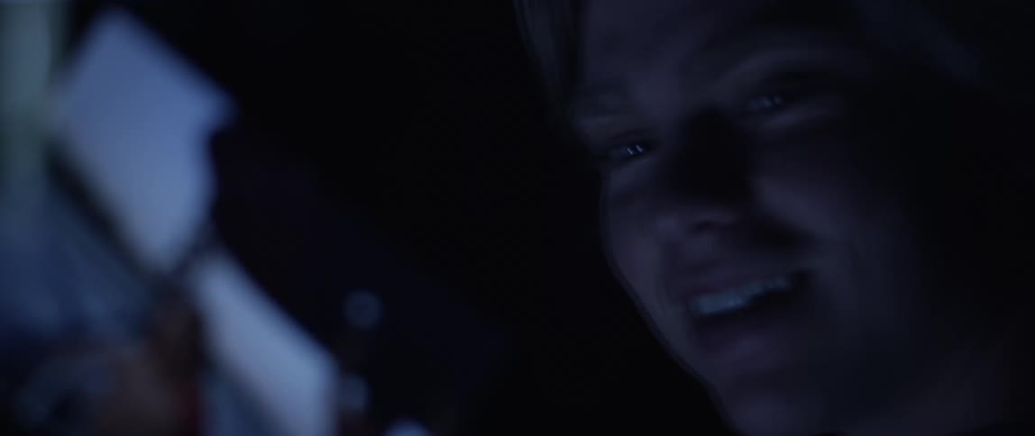A white person smiles and speaks while holding a metal object