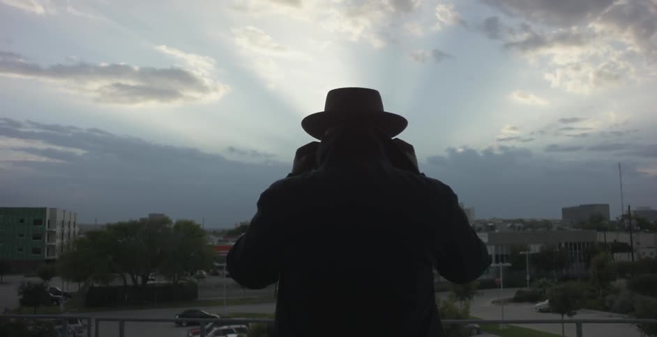 A man standing by a railing puts on glasses