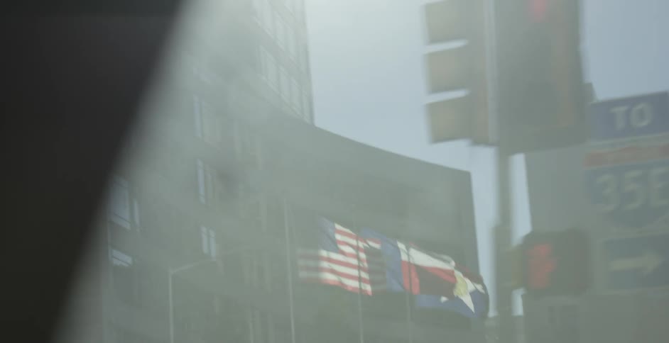 A city has many tall buildings with flags in front of one