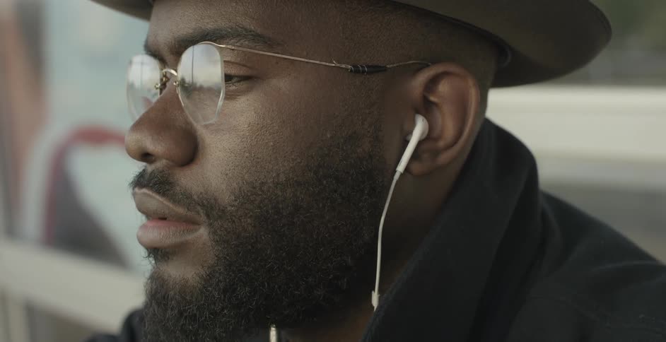 A bearded man with earbuds in his ears