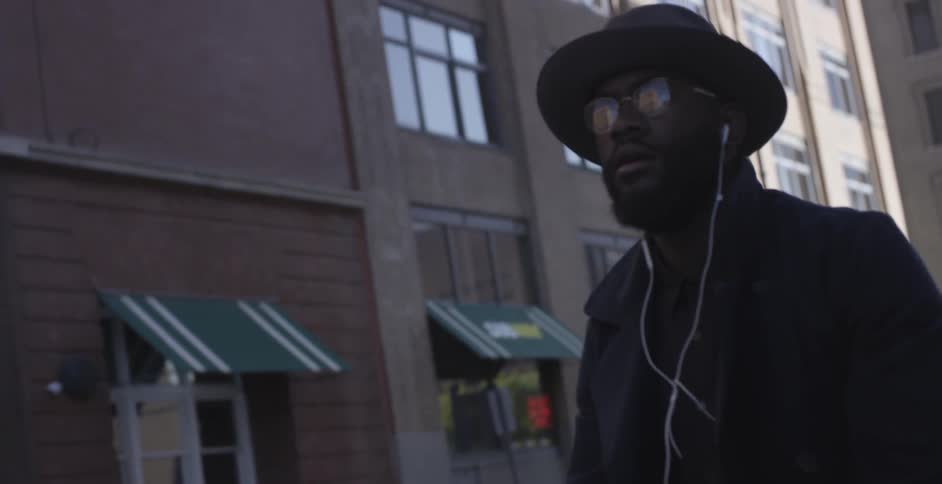 A man in a black hat rides his bike down the street