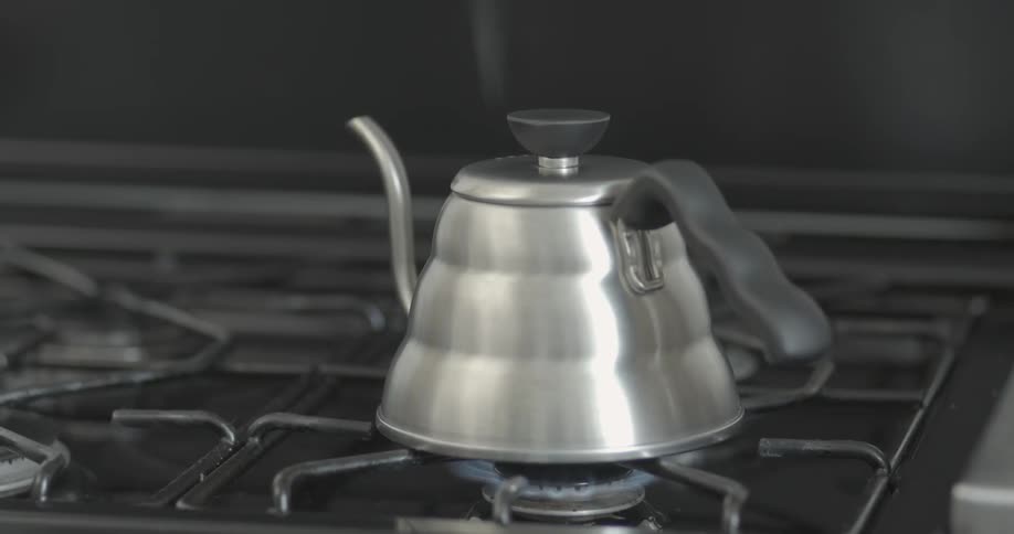 A coffee pot is boiling water on a stove