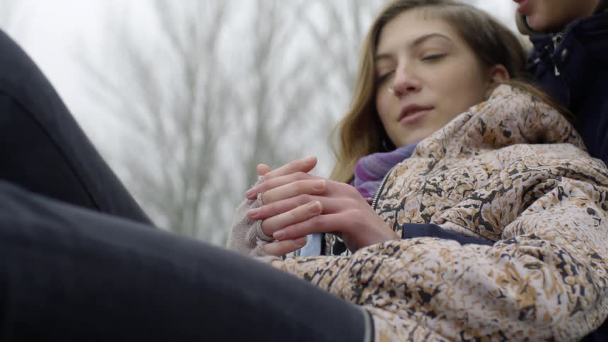 A girl leans against a boy