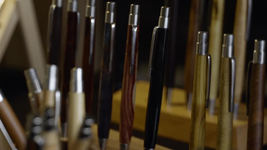 Several pens with wooden barrels are displayed on stands made of blocks of wood