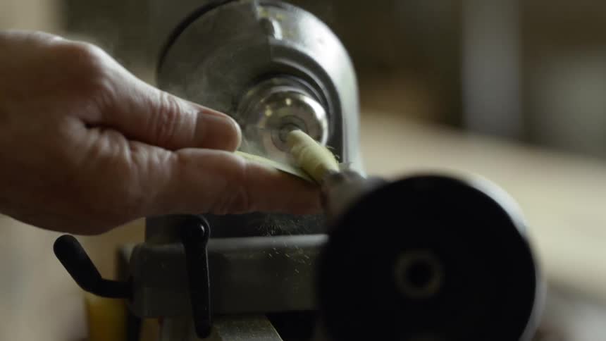 Man uses lathe to turn piece of wood on sanding paper