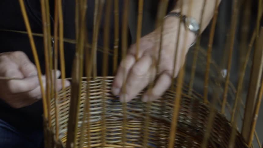 Person sits on floor weaving a basket