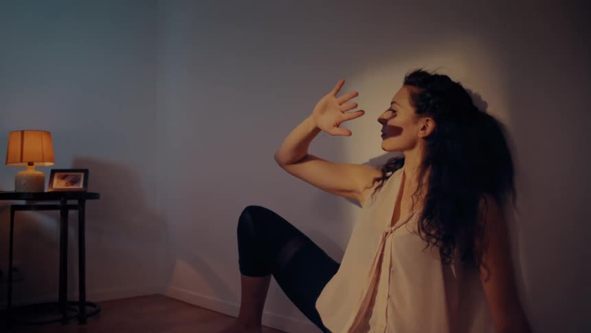 Woman sitting in the floor of a bedroom plays with shadows in the wall