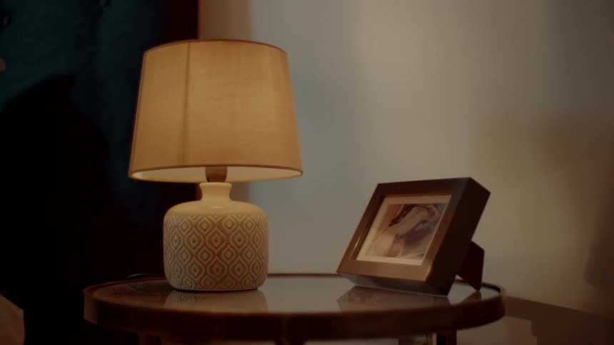 Flicker of light moving across a table lamp and picture frame at night
